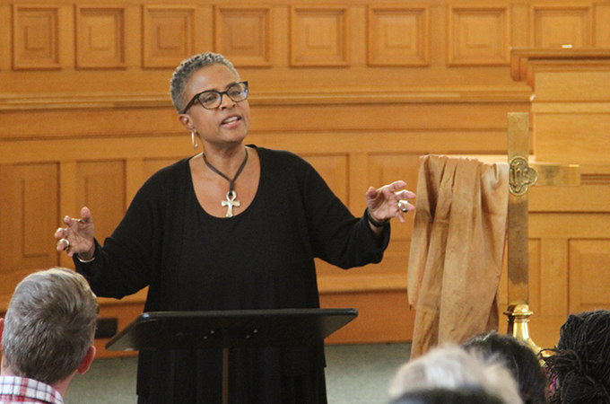 Yvette preaches to an audience from behind a church podium.