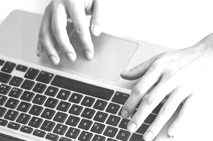 Hands typing on a laptop keyboard.