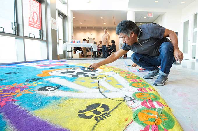 artist sprinkling sand on installation