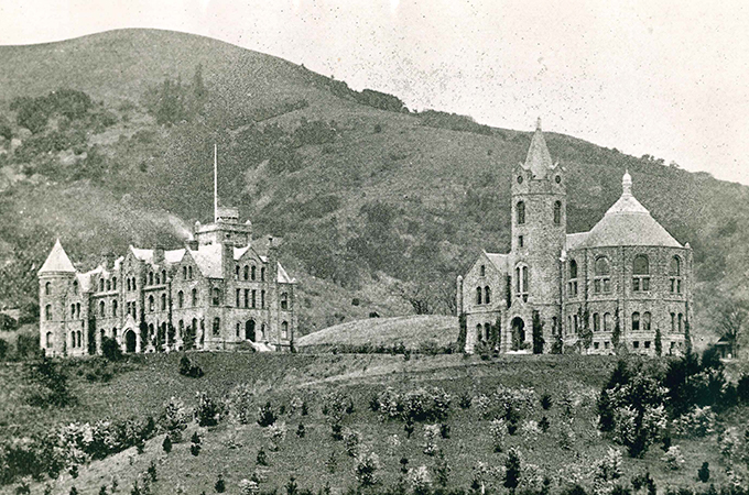 Two buildings sit on a hill in a historic black and white photograph.