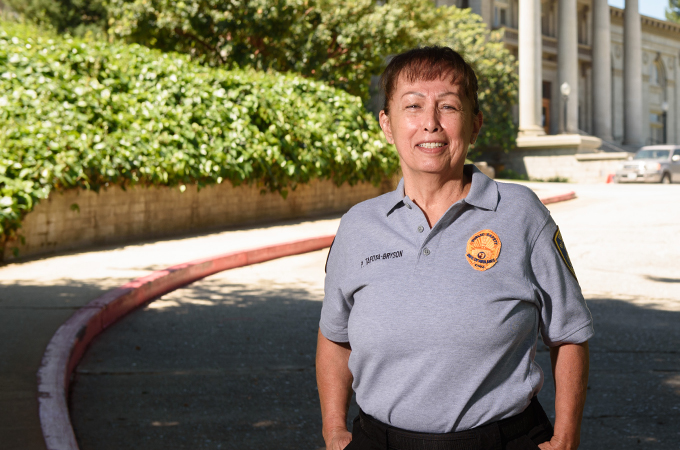 Patricia Tafoya-Bryson stands beneath a tree in the driveway that leads to the Administration Building.