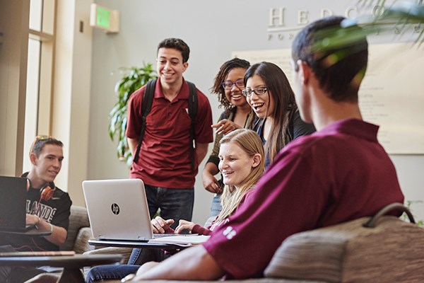 students gathered around a laptop