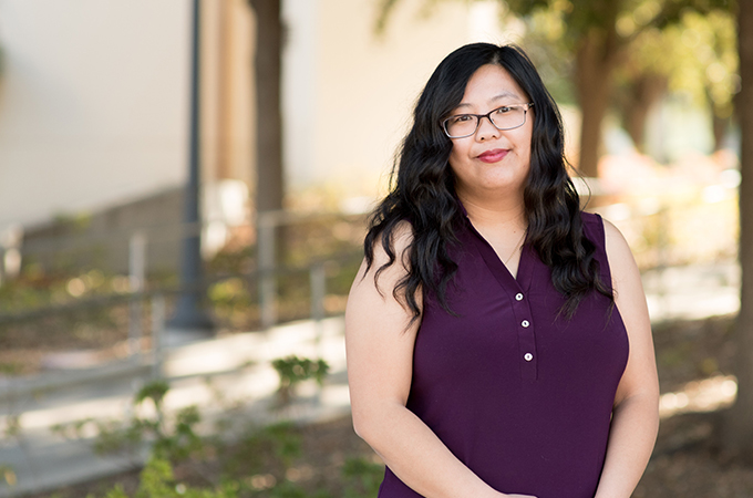 Mai Vang wearing a purple blouse. She is looking and smiling at the camera.